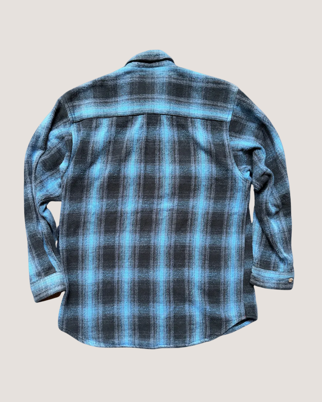 Blue and black plaid shirt on a light gray background