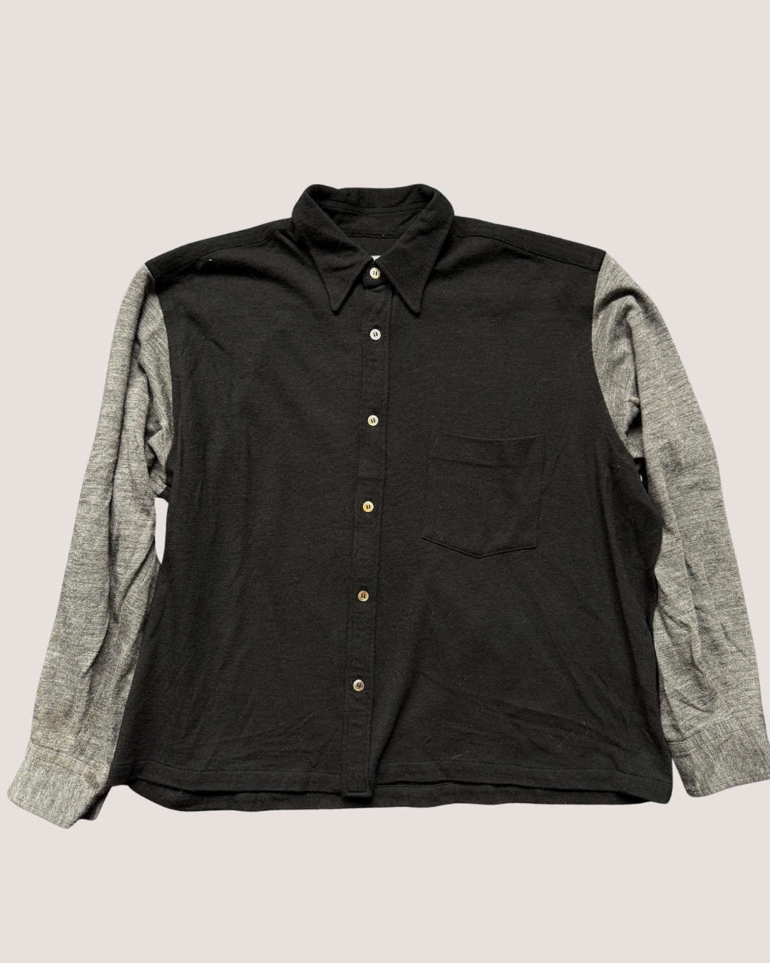 Black shirt with gray sleeves on a light beige background