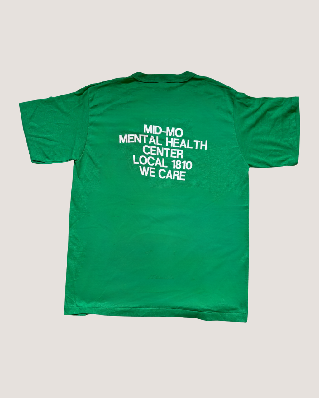Green t-shirt with text on the back on a light gray background