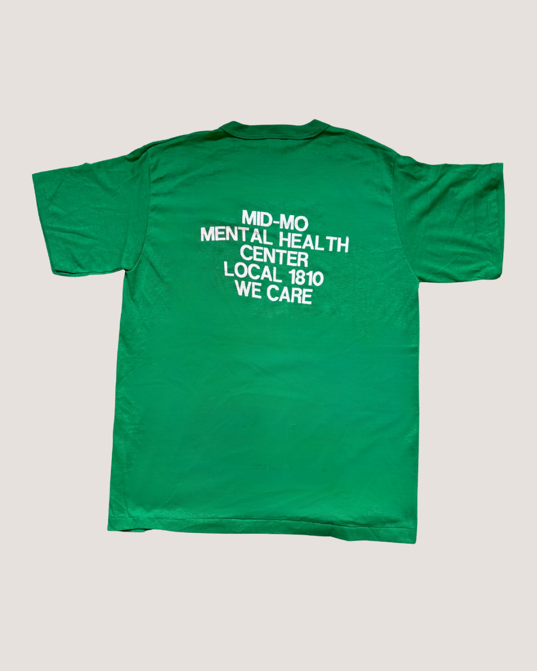 Green t-shirt with text on the back on a light gray background