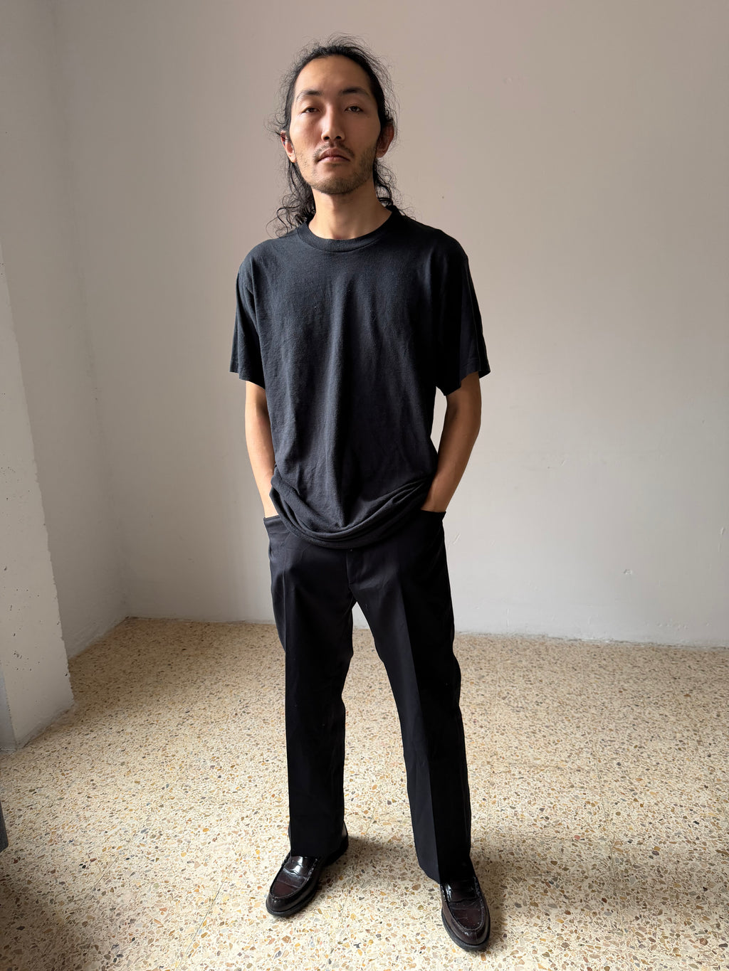 Man wearing a black t-shirt Athletic Duke and pants standing in a minimalistic room.