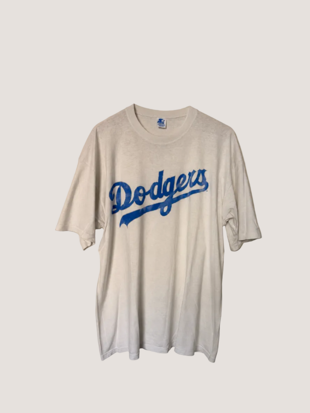 White t-shirt with 'Dodgers' logo on a beige background