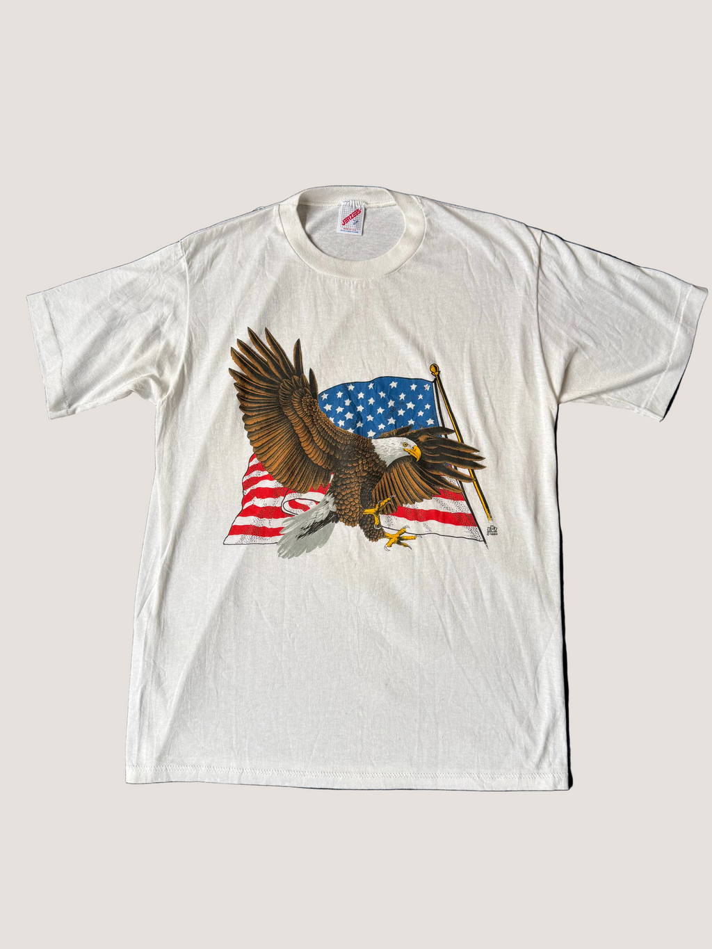 White t-shirt with an eagle and American flag design on a light gray background