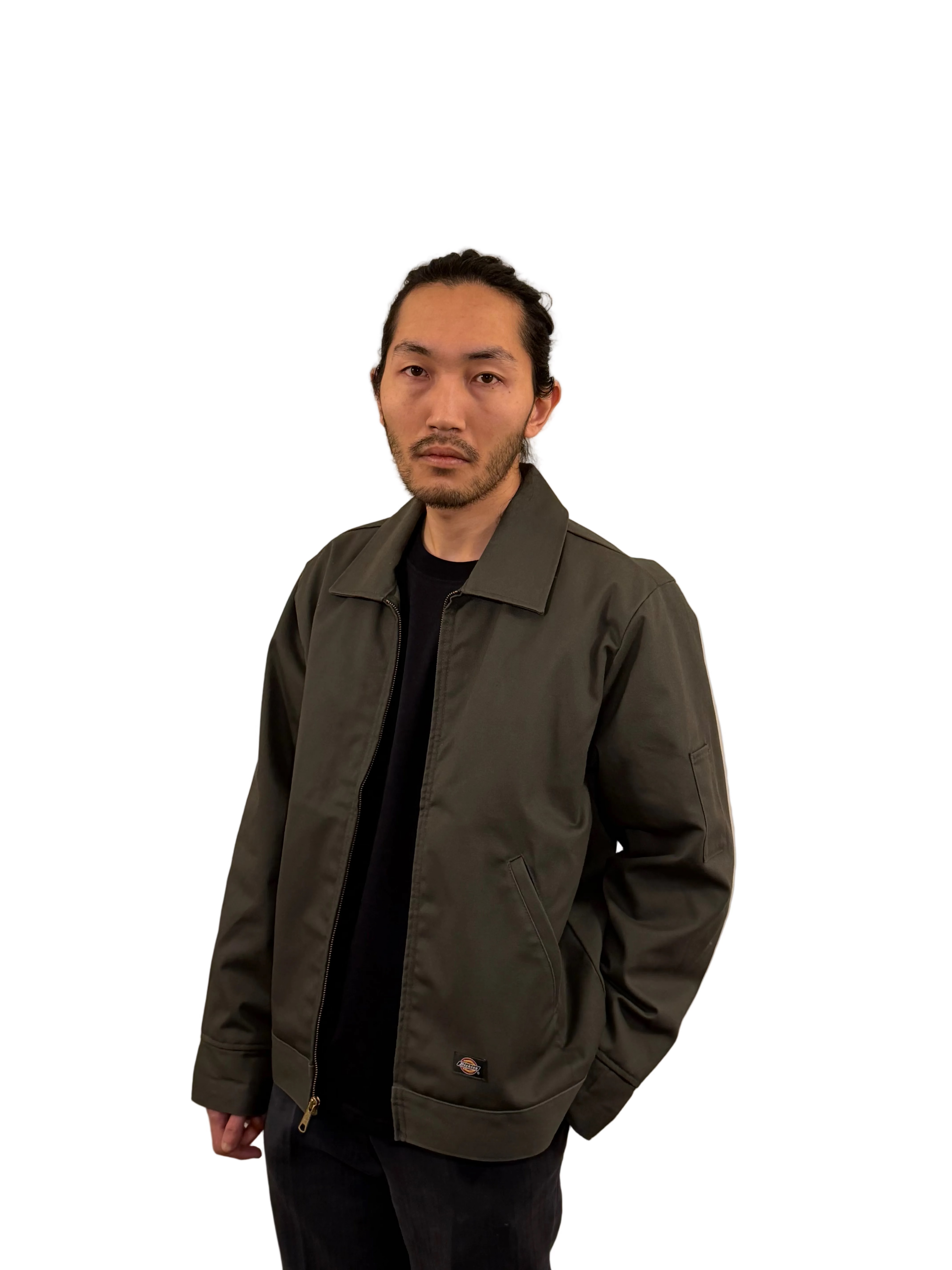 Man wearing a dark green jacket against a beige background
