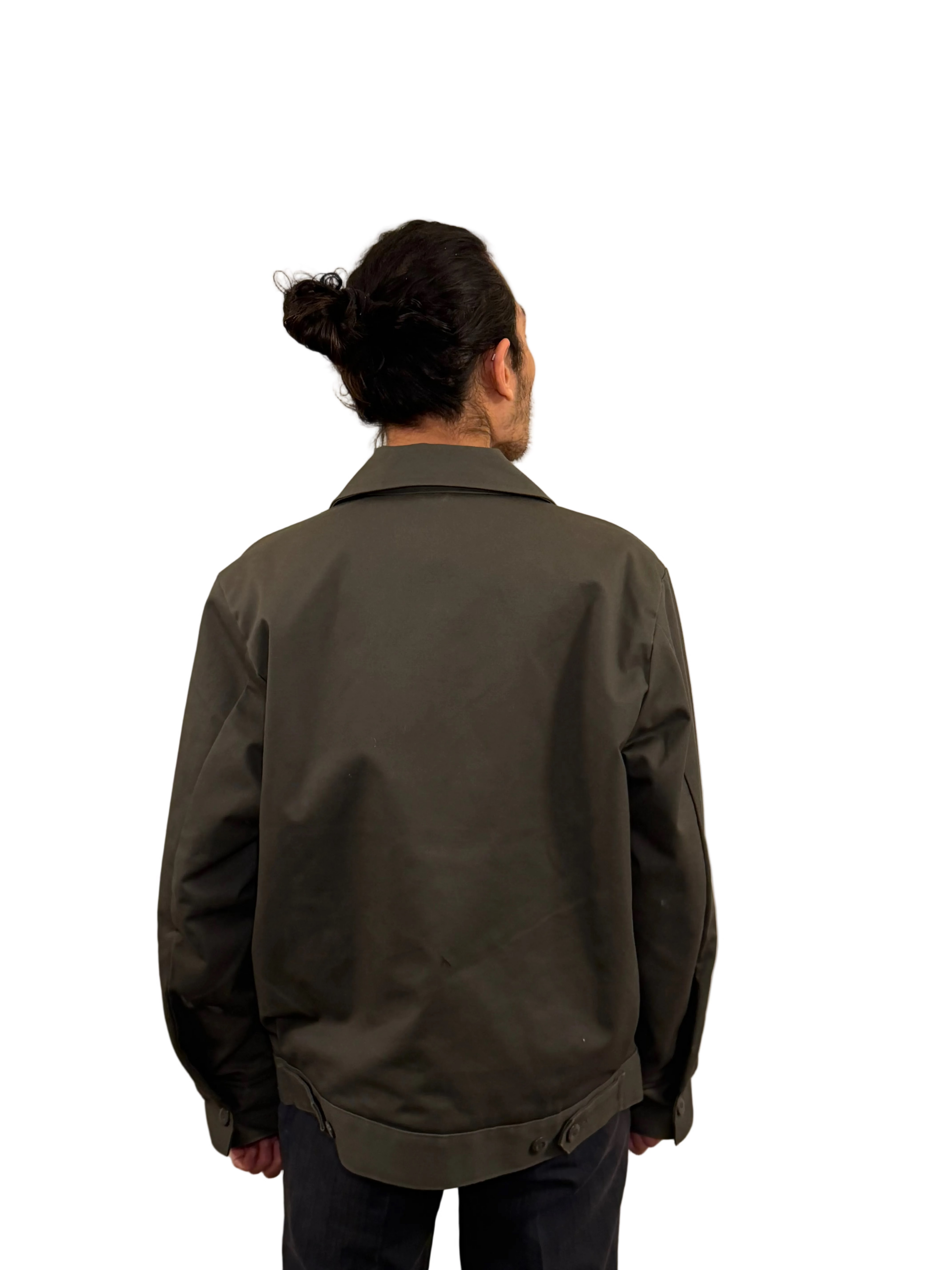 Person wearing a dark green jacket against a plain background