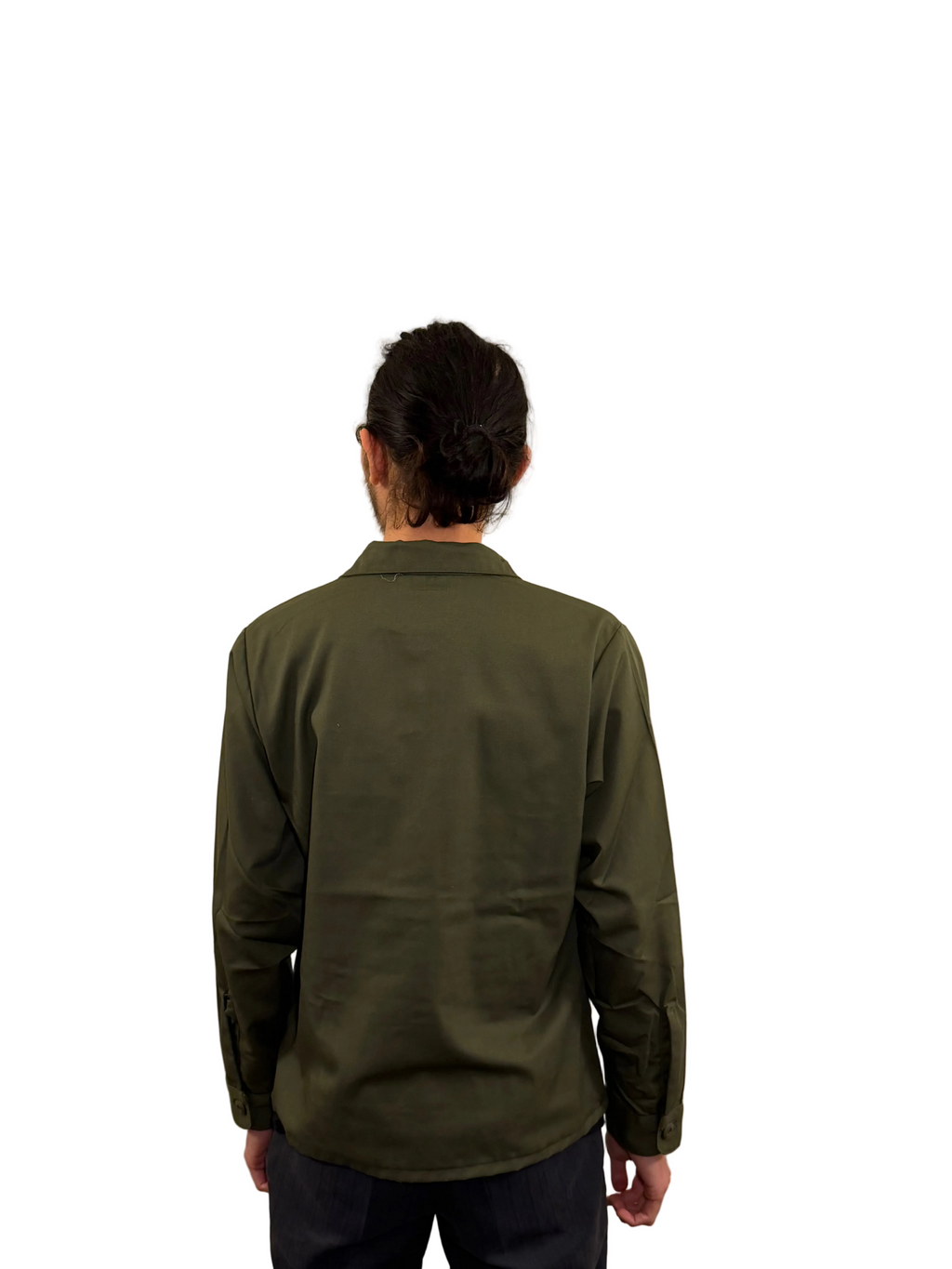 Person wearing a green shirt against a beige wall