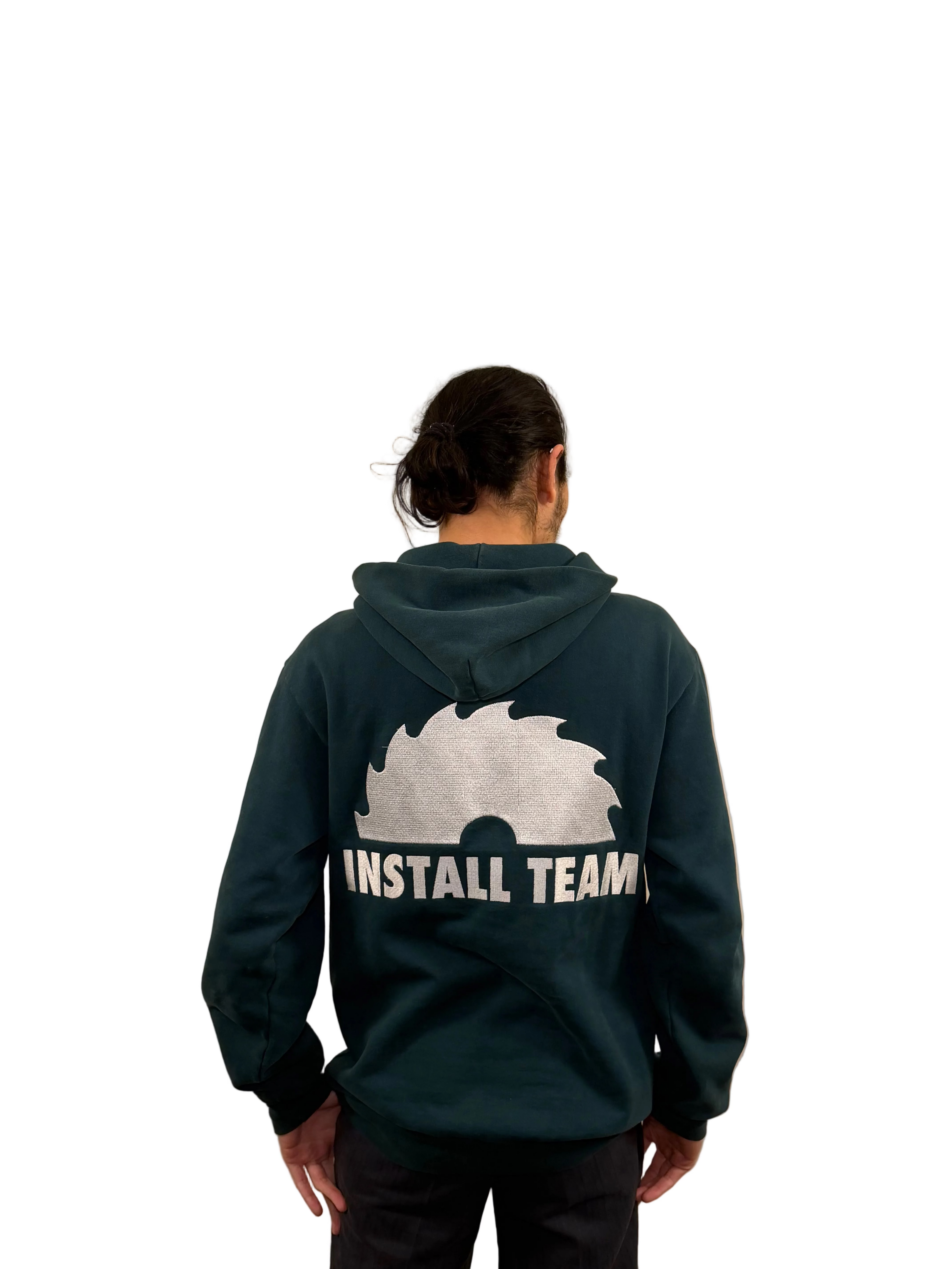Person wearing a dark green hoodie with 'Install Team' text on the back against a beige wall.
