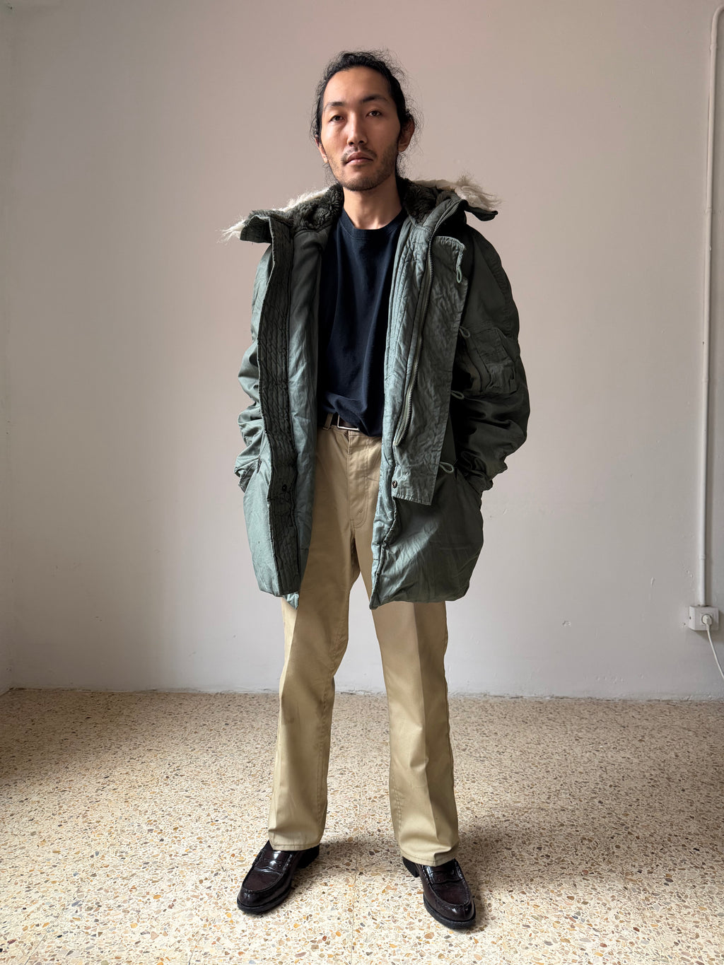 Person wearing a green N-3B-Parka jacket with a fur-lined hood in an indoor setting