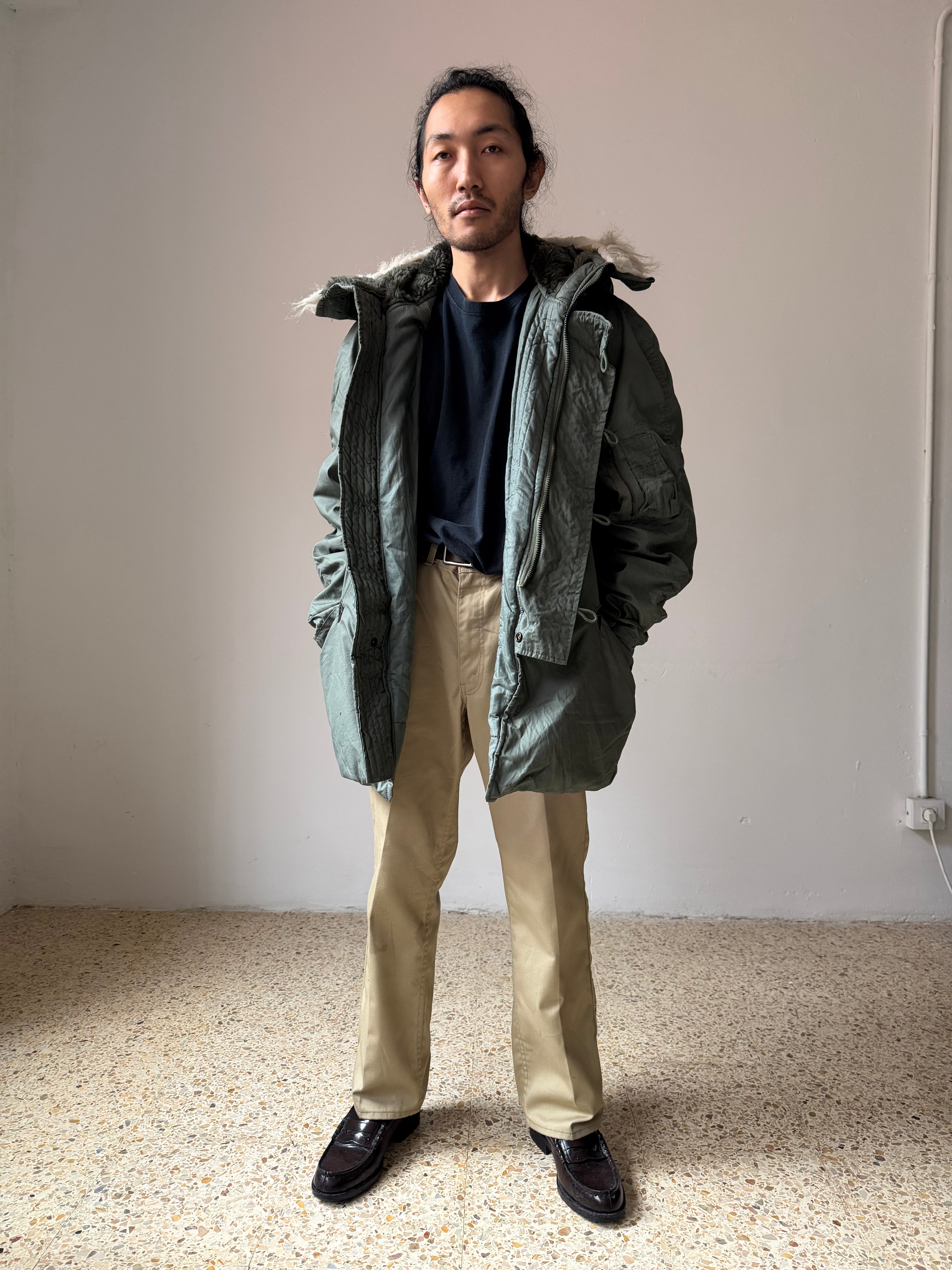 Person wearing a green N-3B-Parka jacket with a fur-lined hood in an indoor setting