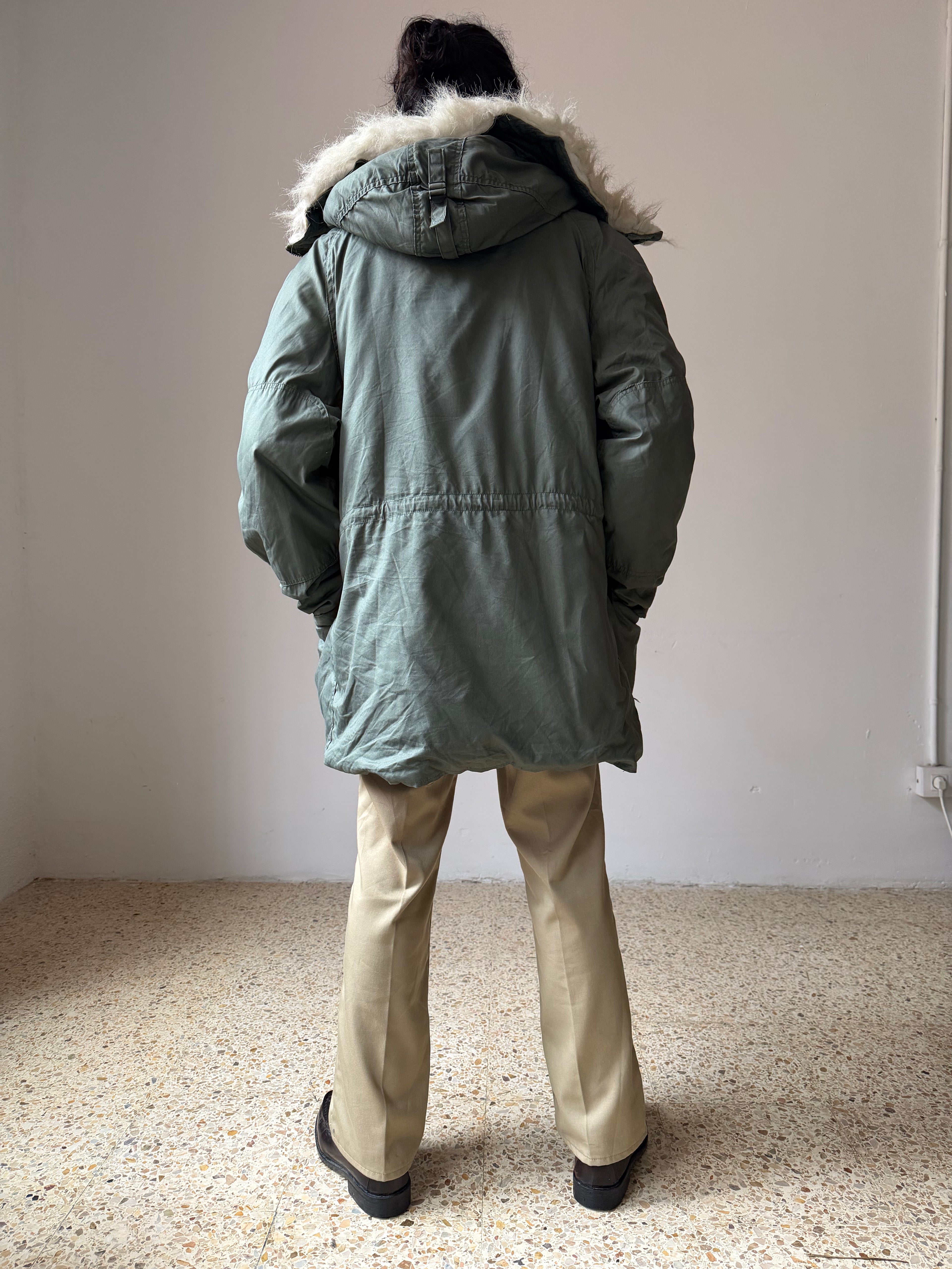 Person wearing a green N-3B-Parka with fur-lined hood in an indoor setting
