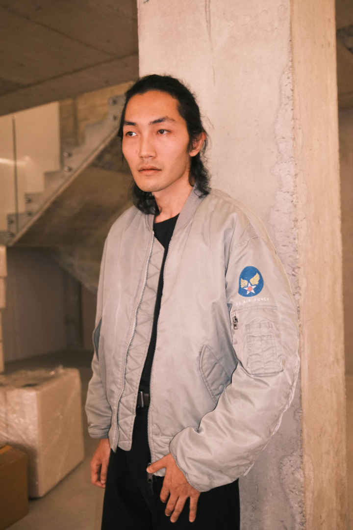 Person wearing a light gray jacket with a logo in an indoor setting