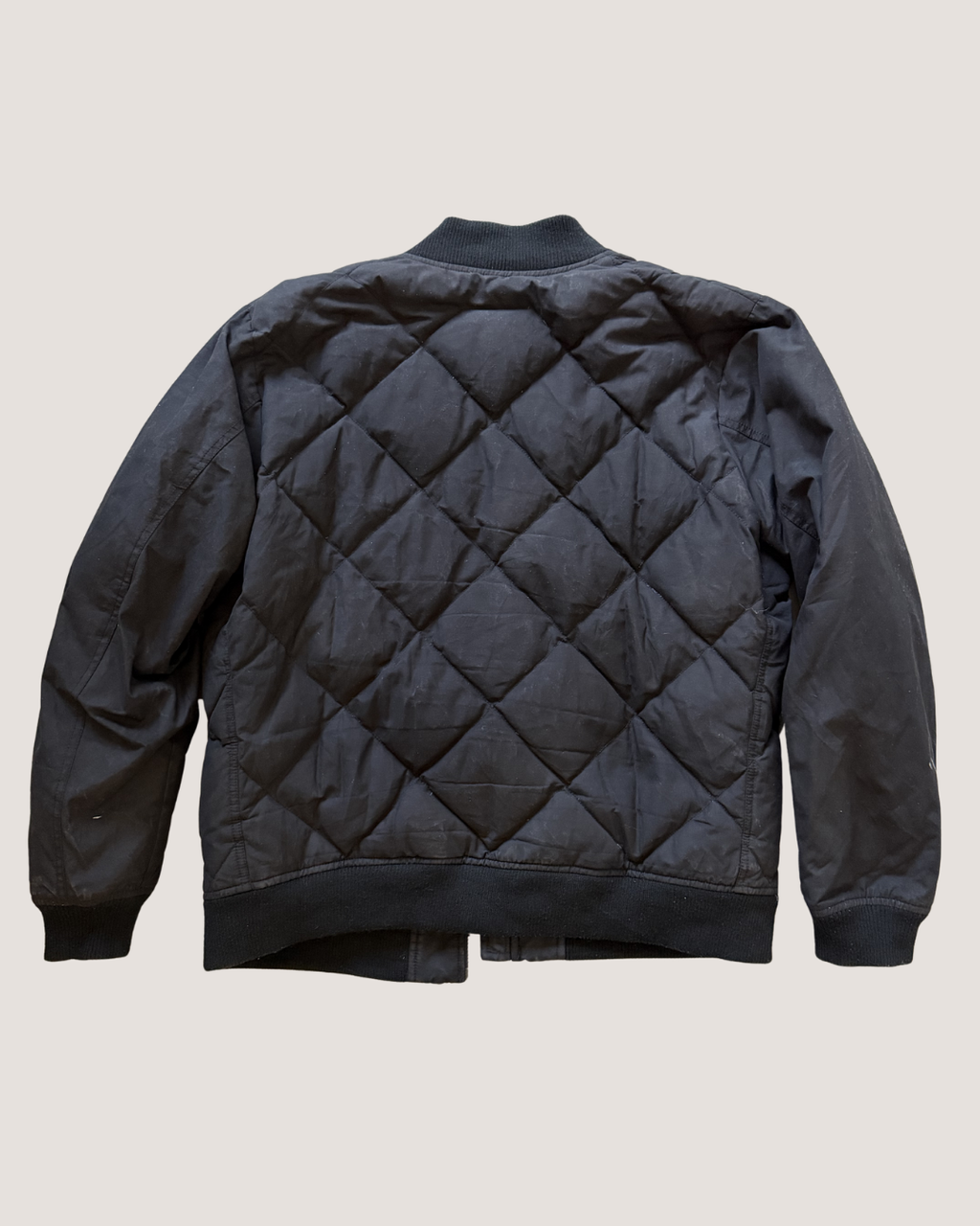 Black quilted jacket on a beige background