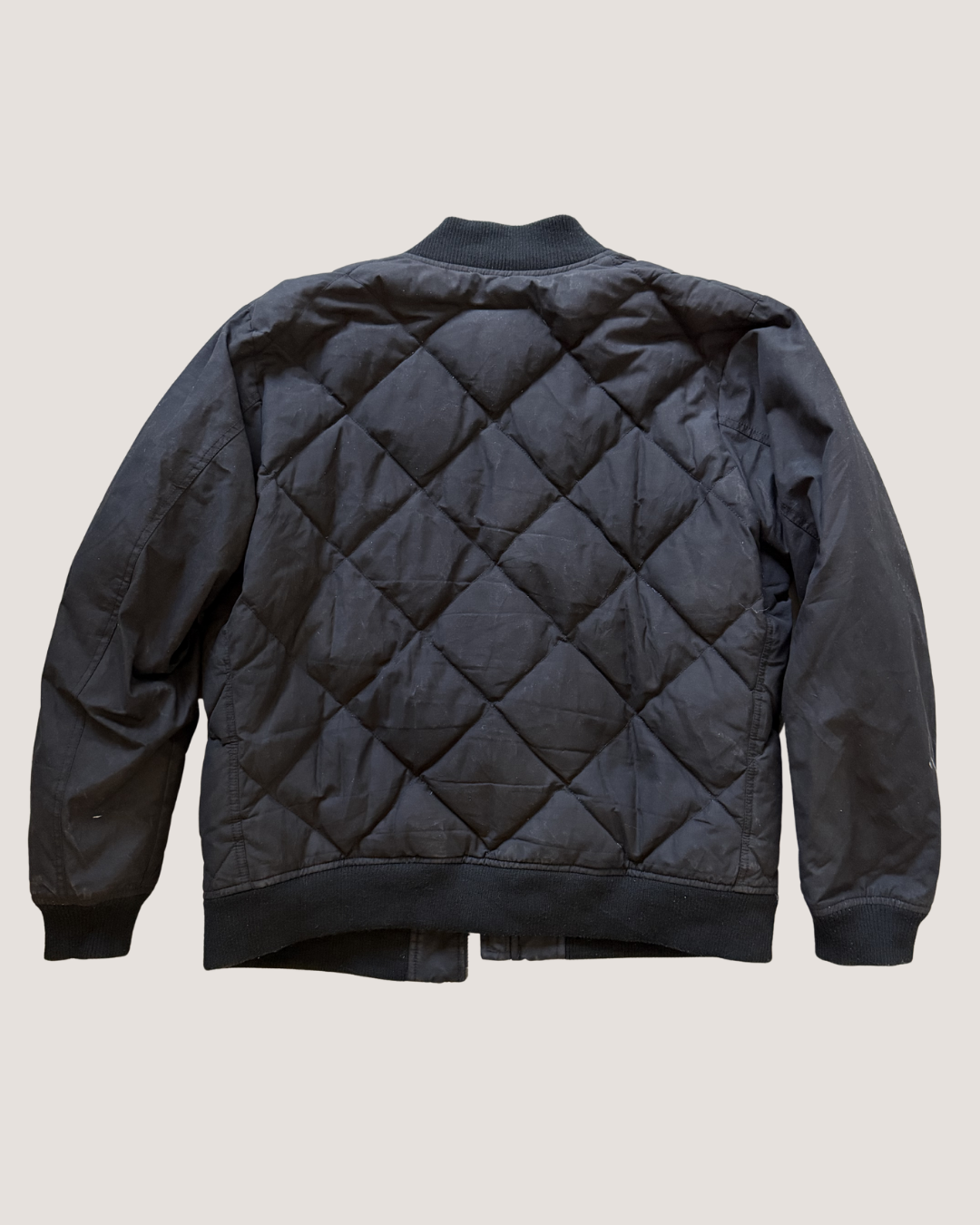 Black quilted jacket on a beige background