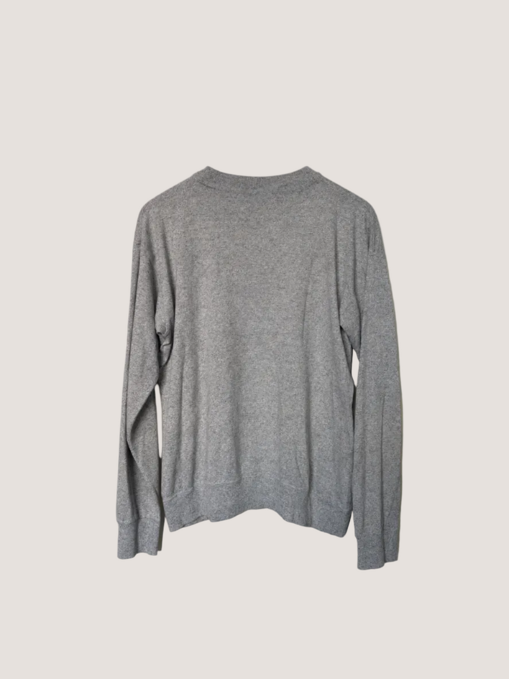 Gray sweater hanging against a plain wall