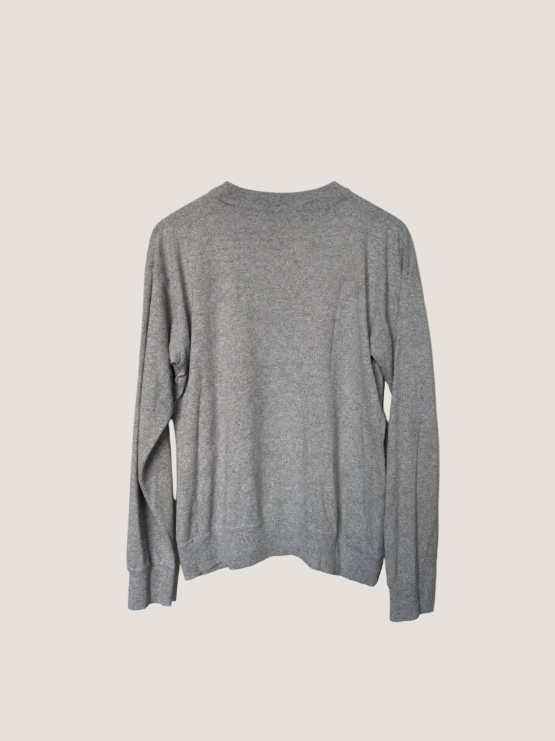 Gray sweater hanging against a plain wall
